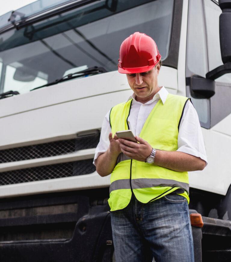 Worker in high-vis vest and hardhat looking on phone