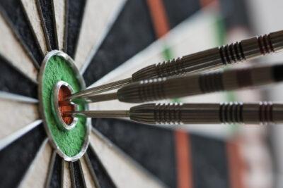 three darts hitting the bullseye on a dart board