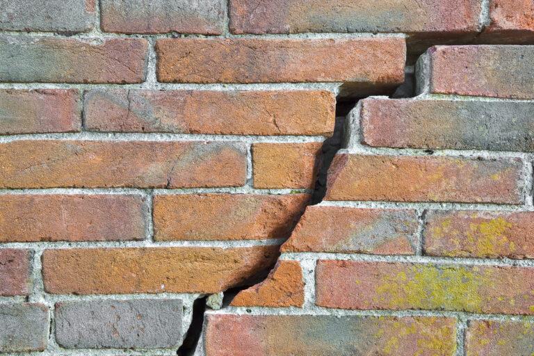 Dangerous old exposed cracked brick wall